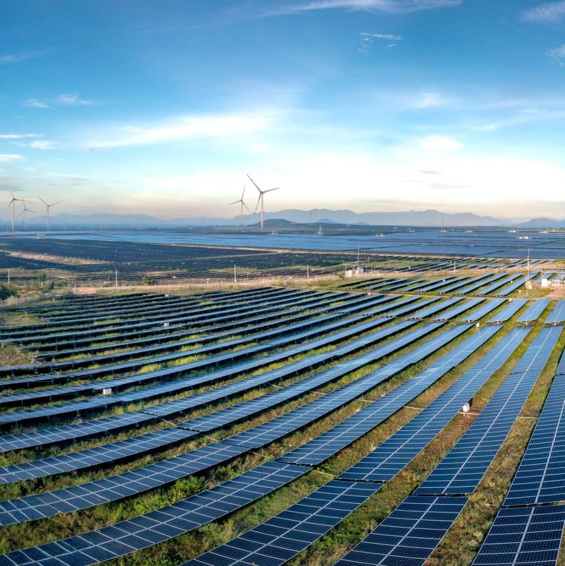 Solar panels and wind turbines under a blue sky